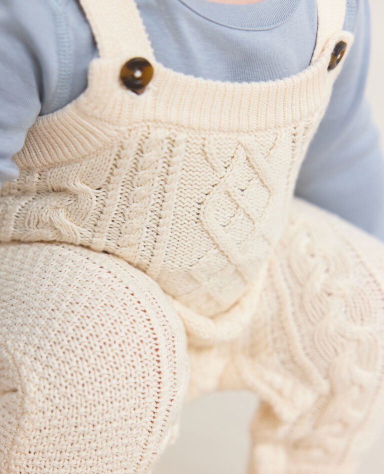 baby in white cotton overalls