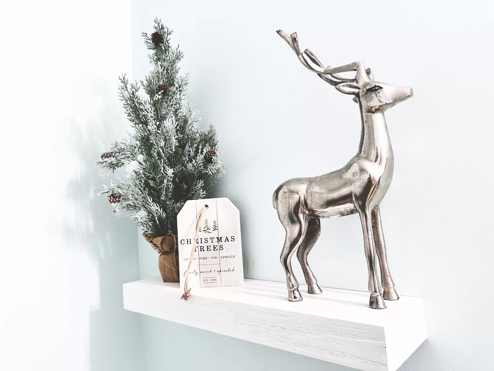 Tiny Christmas tree and metal deer on shelf