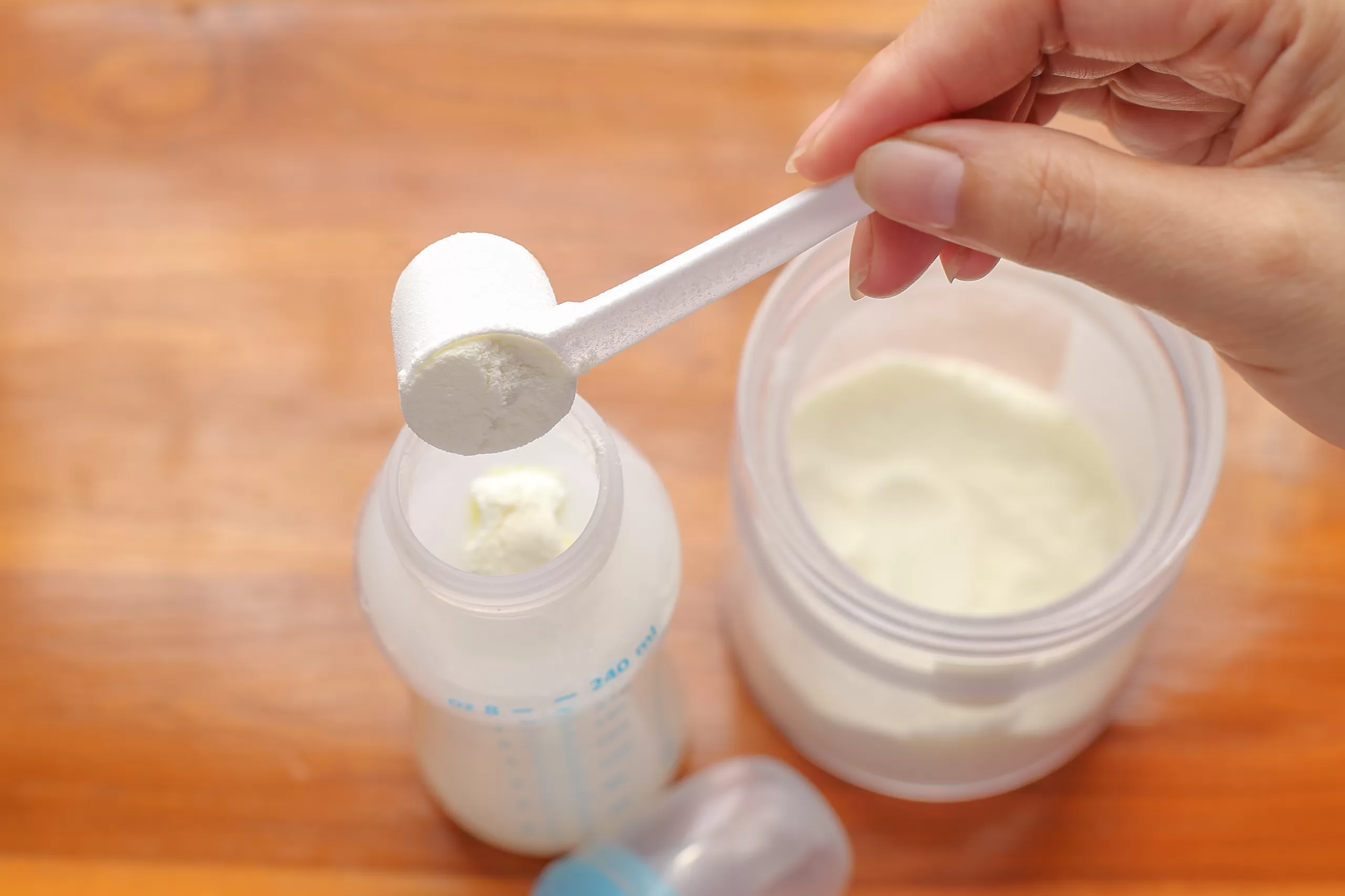 womans hand putting formula into bottle