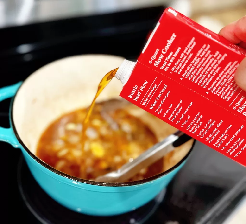 beef broth being poured into dutch oven