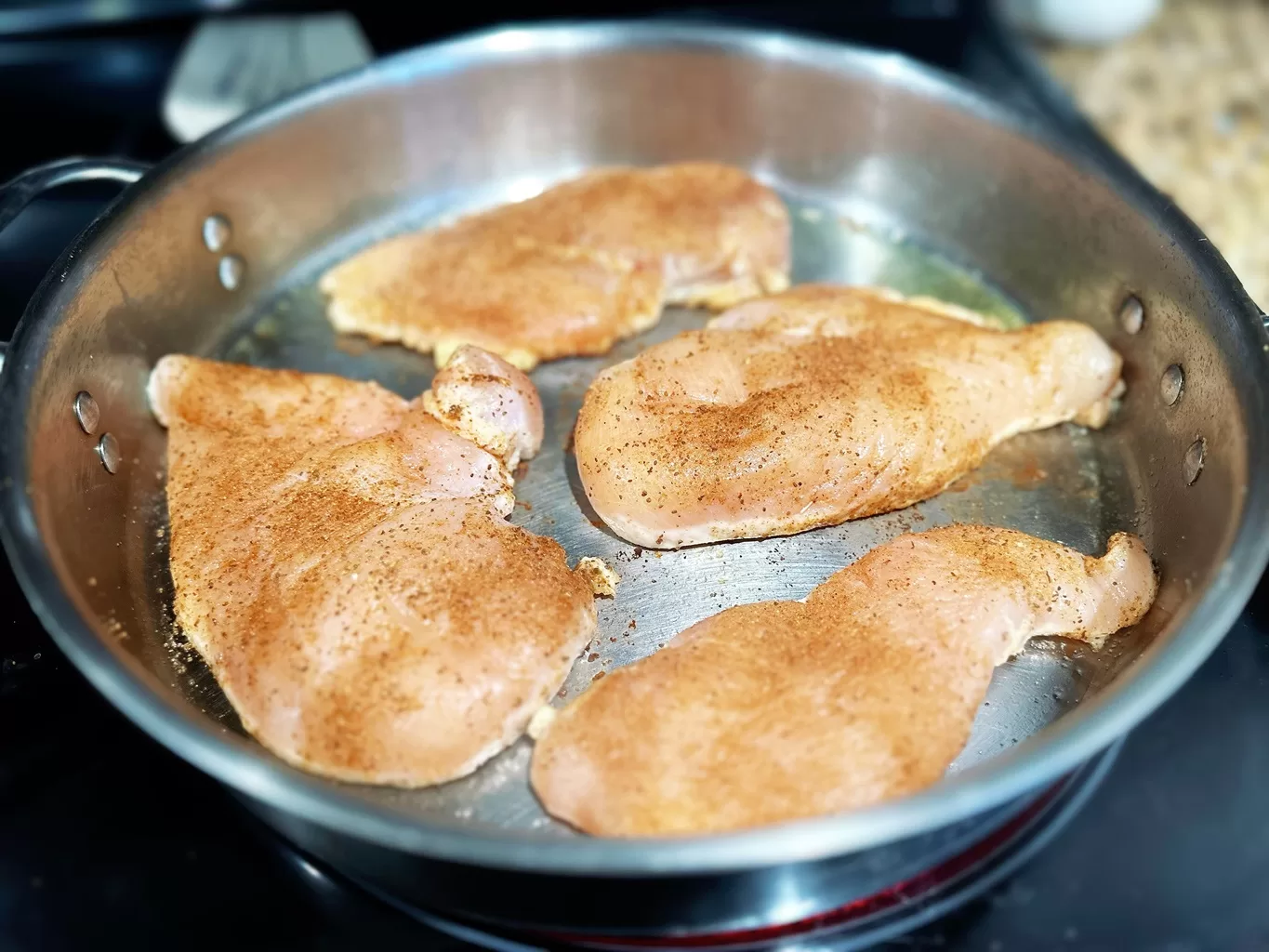 raw chicken breasts searing in a pan