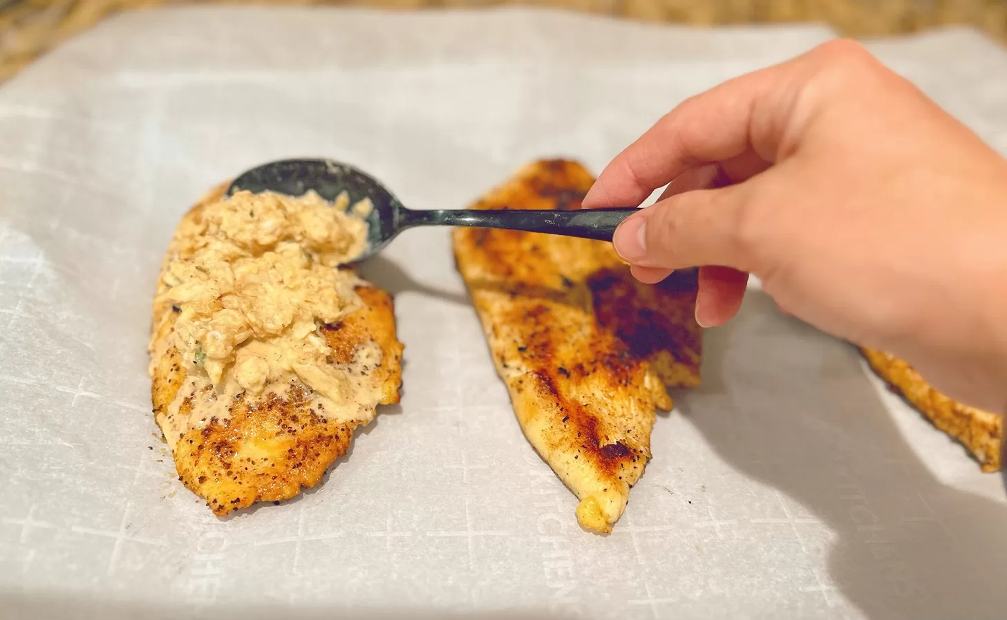 chicken breast with crab imperial being placed on top with a spoon