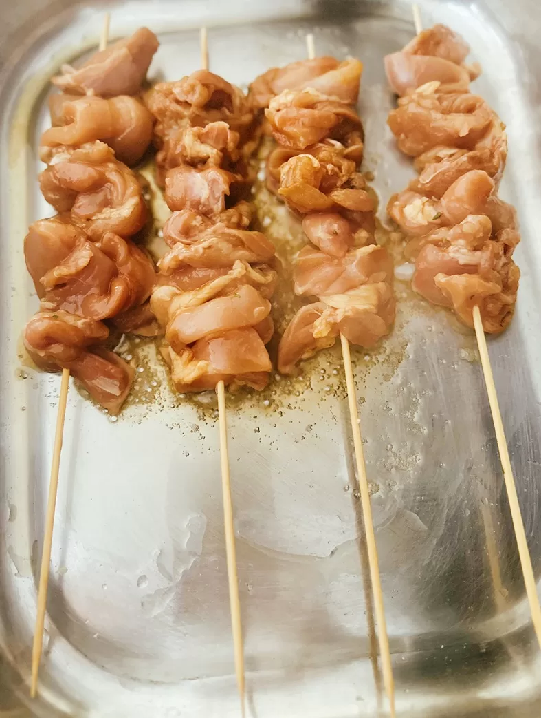 skewered chicken searing in a pan