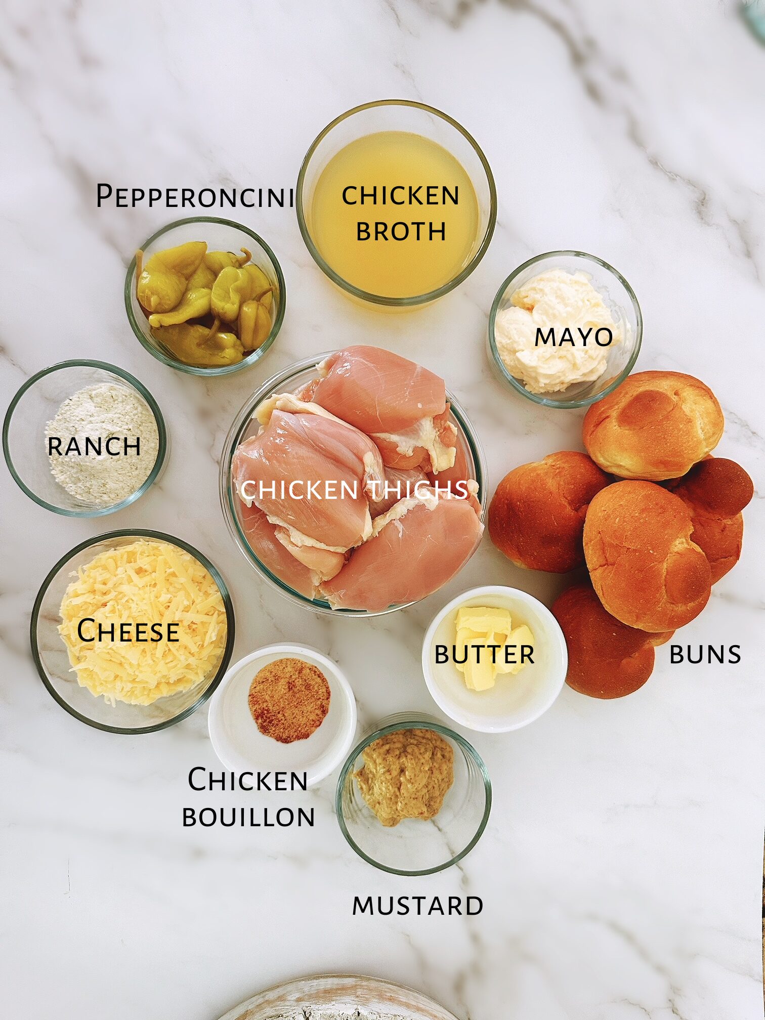 Ingredients for chicken sliders laid out on a  white marbled counter top