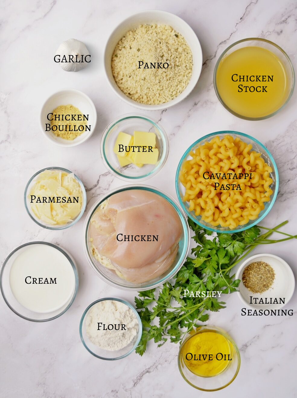 Labeled ingredients for garlic parmesan chicken pasta on top of a white marbled background