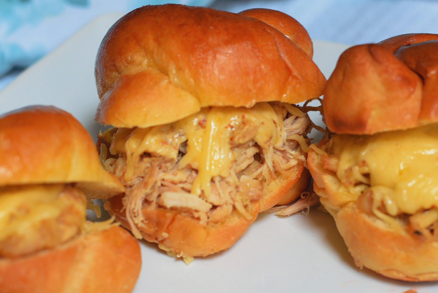 cheesy chicken sliders on a white plate