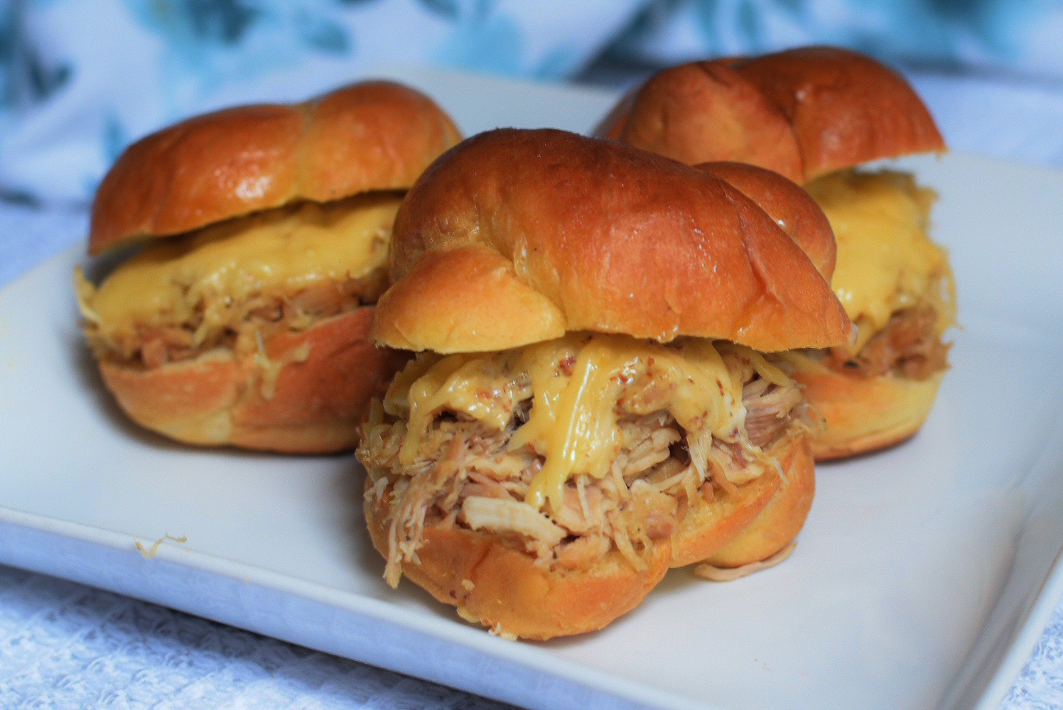 cheesy pulled chicken sliders on a white plate