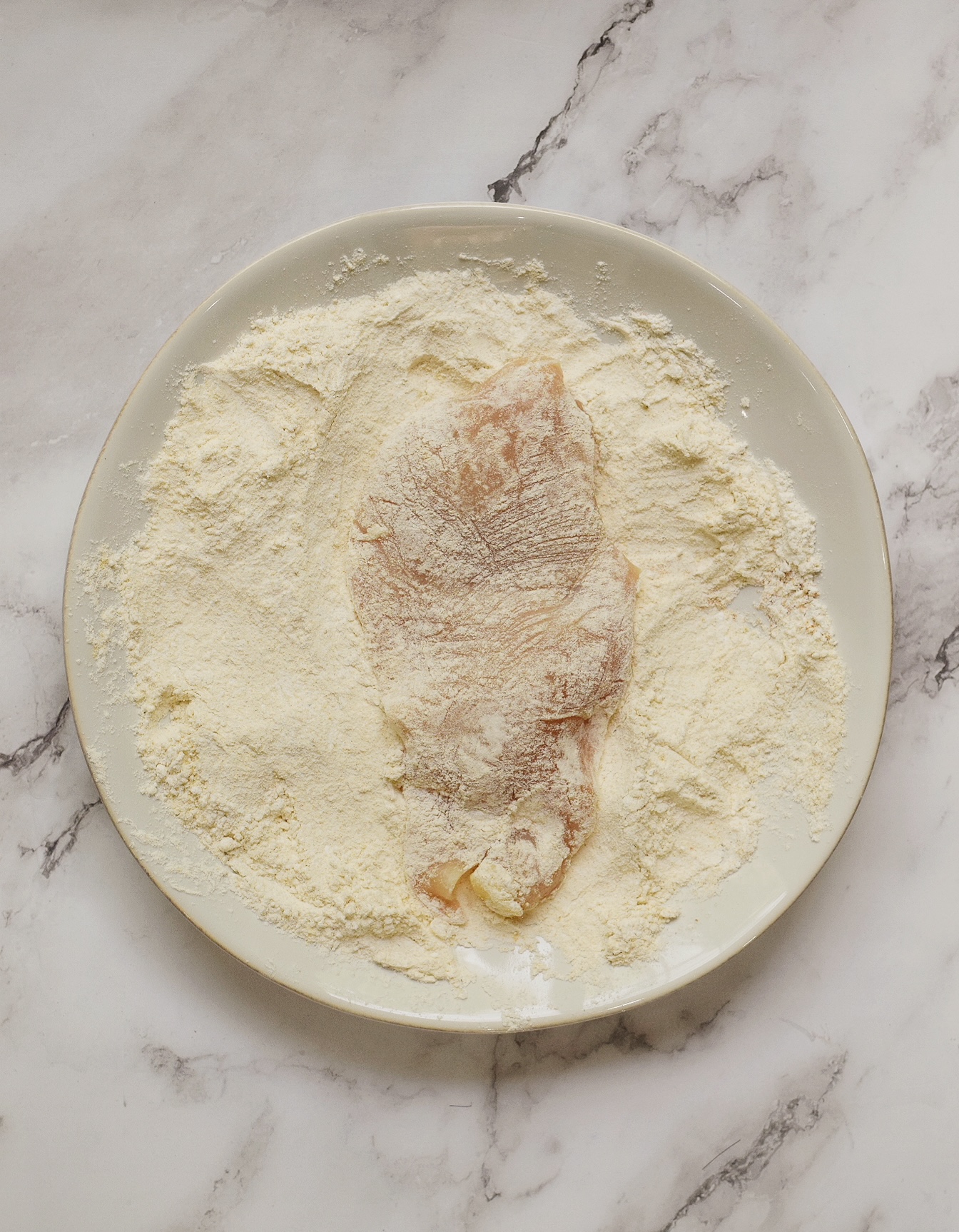 chicken coated in flour mixture on a white plate