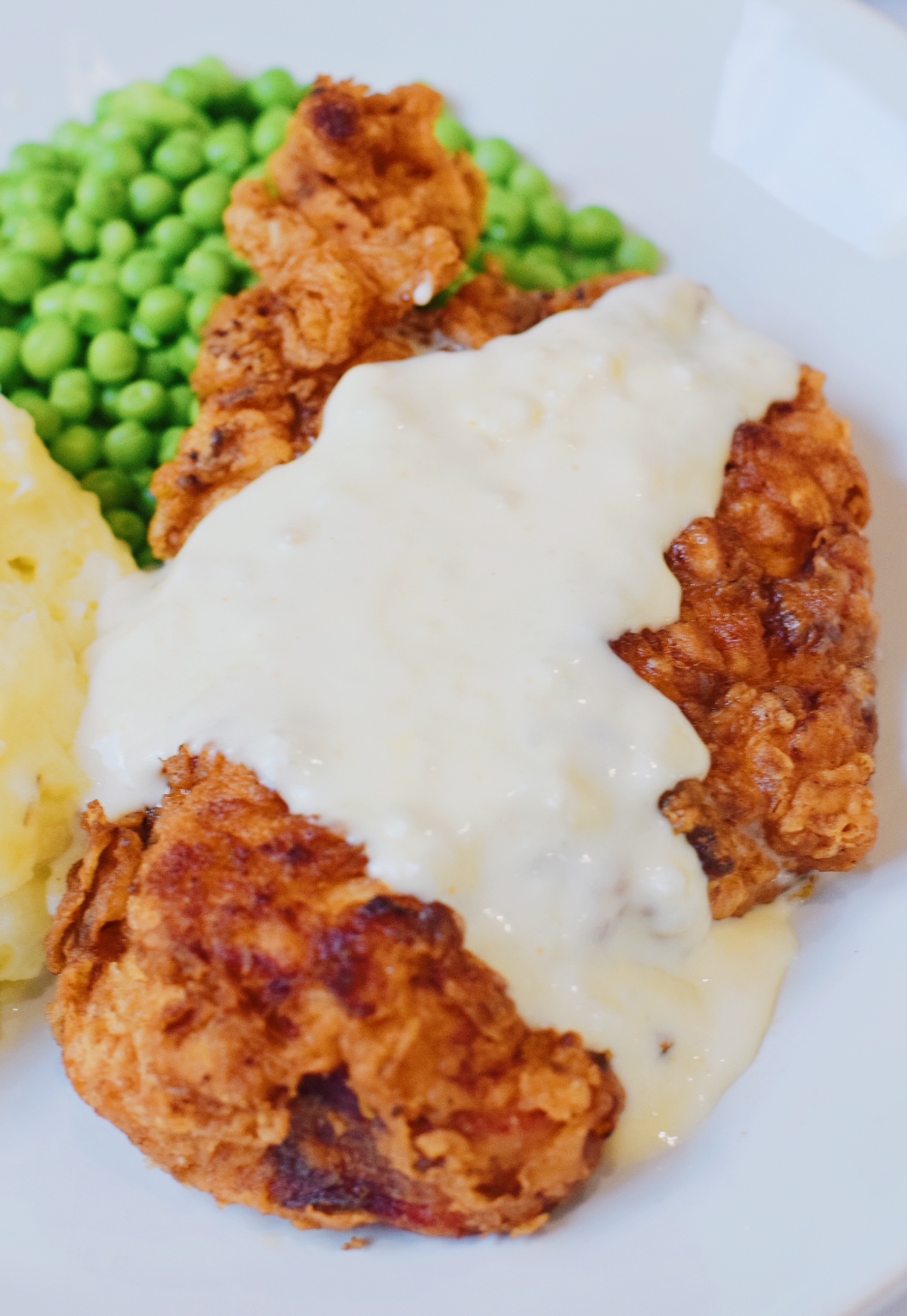 Chicken fried chicken with country gravy recipe plated with peas and mashed potatoes