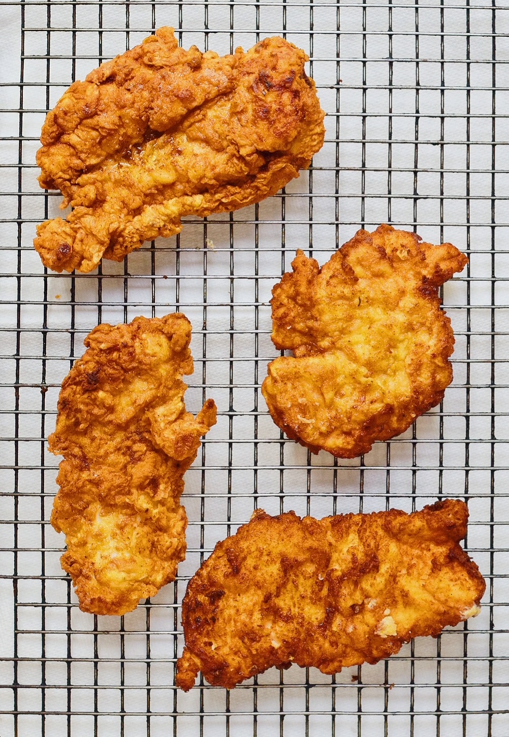 4 pieces of golden fried chicken cooling on a wire rack