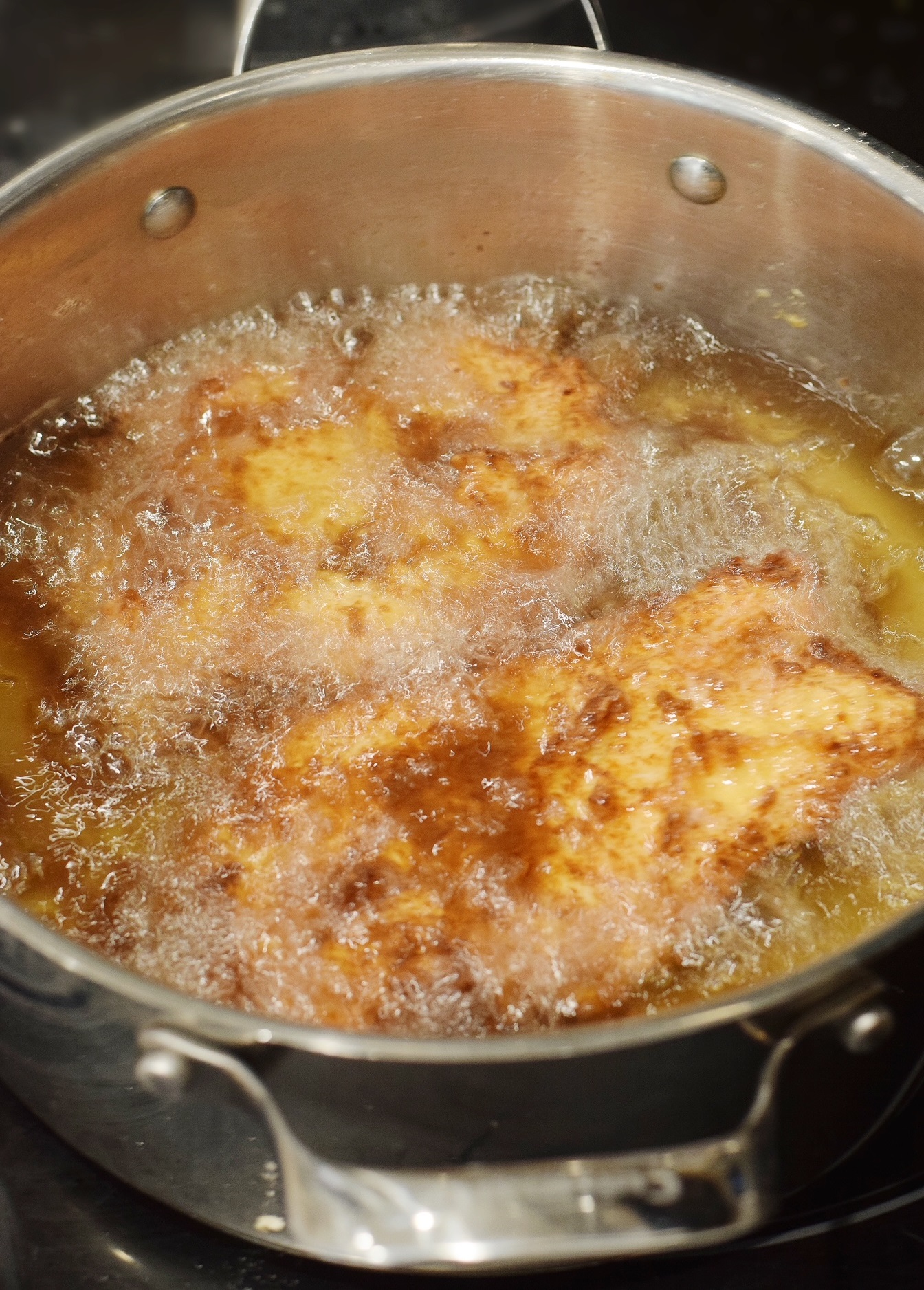 chicken frying in a pot of oil