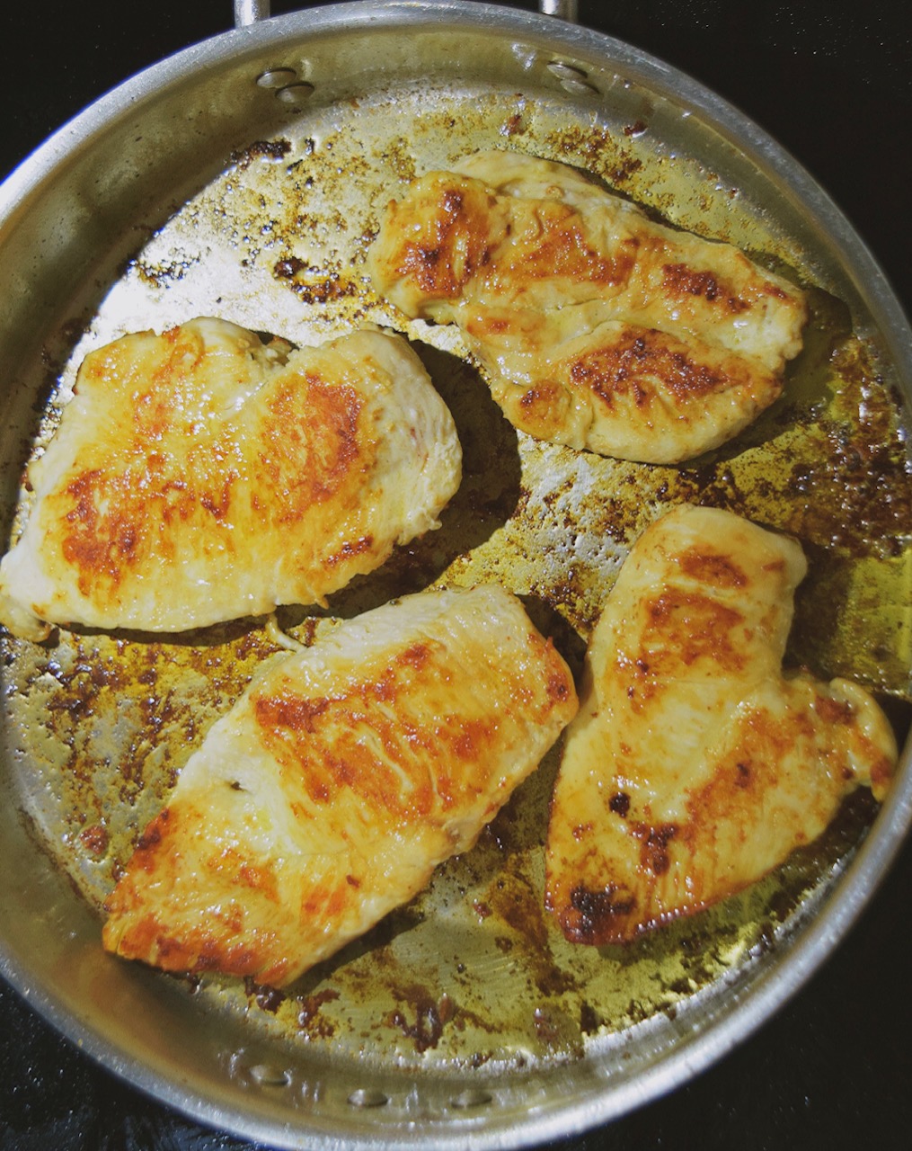 chicken breasts pan searing in a frying pan