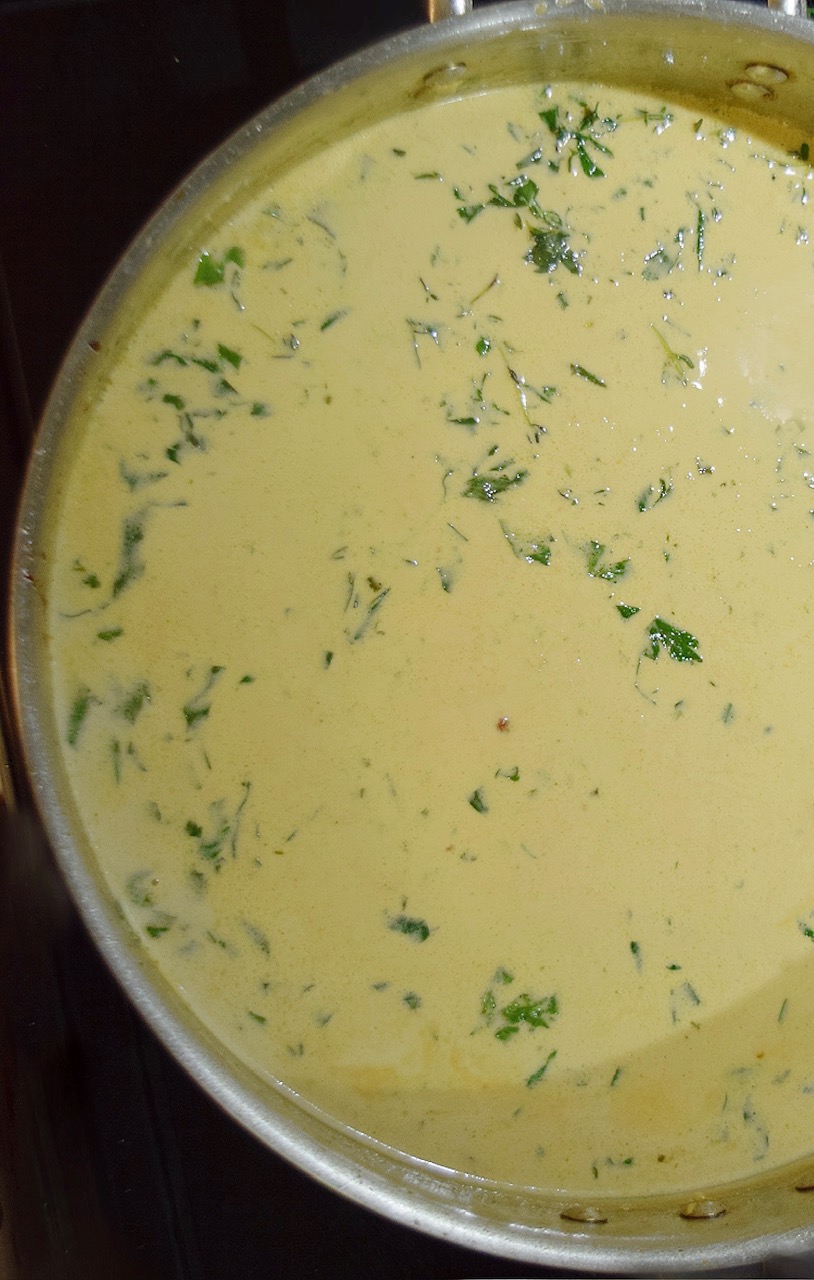 creamy boursin cheese sauce simmering with garlic and herbs in a pan