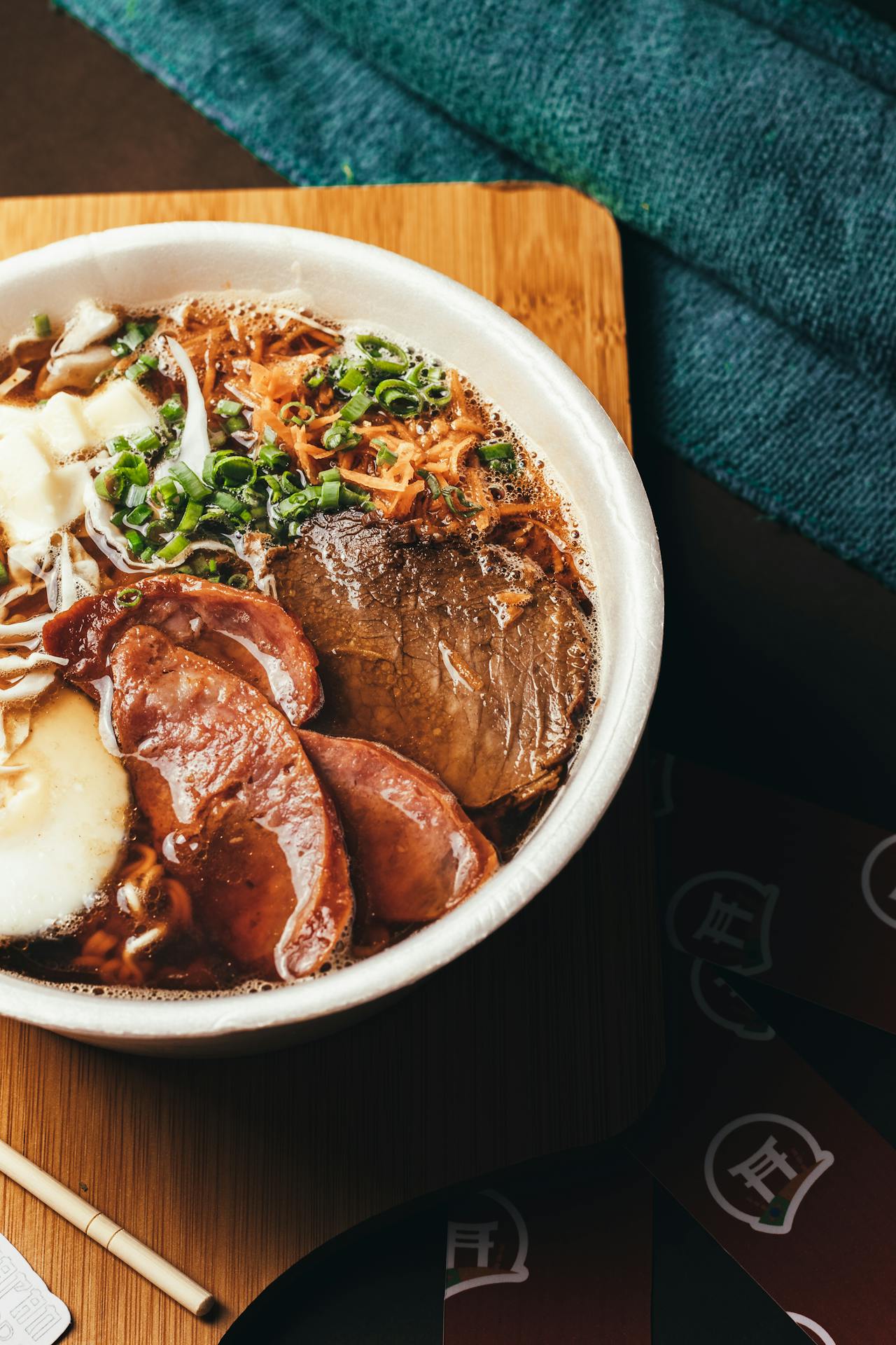 pork ramen in a white bowl on a wood cutting board