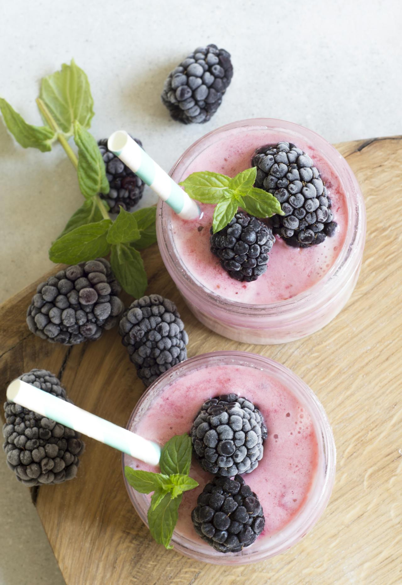 purple smoothies with frozen blackberries and mint leaves with a straw