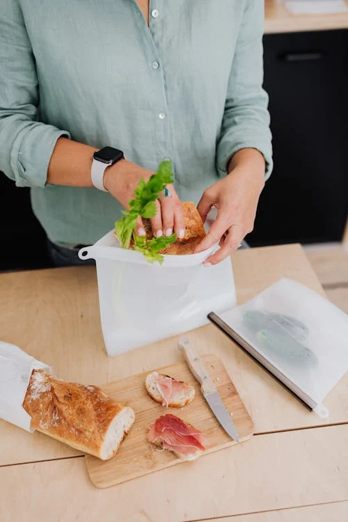 woman putting food into a freezer bag to meal prep