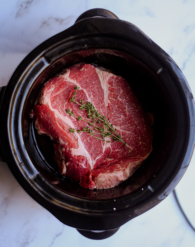 beef chuck roast in a crockpot with fresh thyme