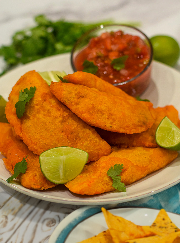 colombian empanadas served with salsa topped with cilantro and fresh lime