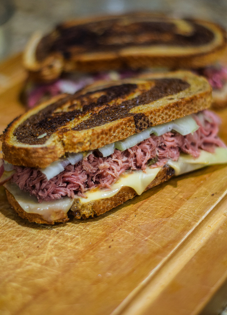 reuben sandwiches on a wood chopping board