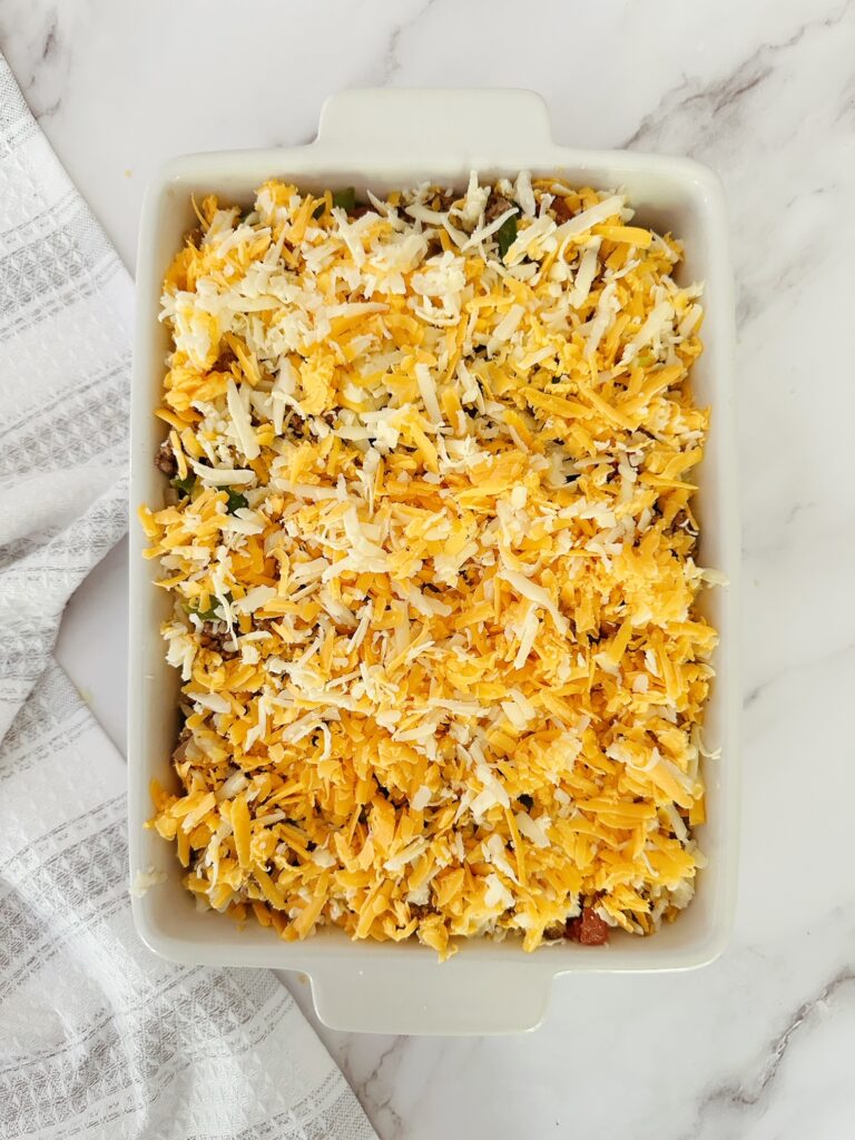 white porcelain casserole dish filled with keto mexican ground beef casserole mix topped with cheese