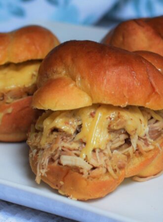 cheesy pulled chicken sliders on a white plate