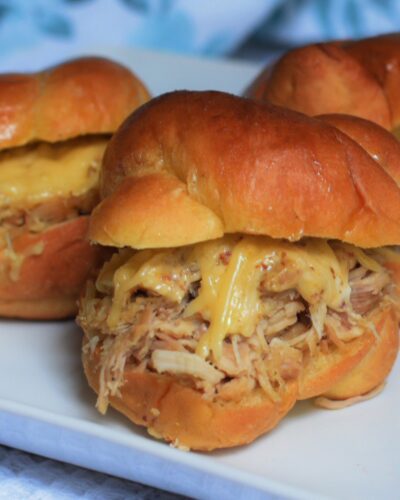 cheesy pulled chicken sliders on a white plate