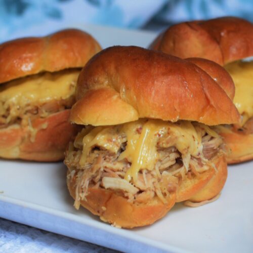 cheesy pulled chicken sliders on a white plate