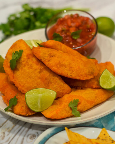 colombian empanadas served with salsa topped with cilantro and fresh lime